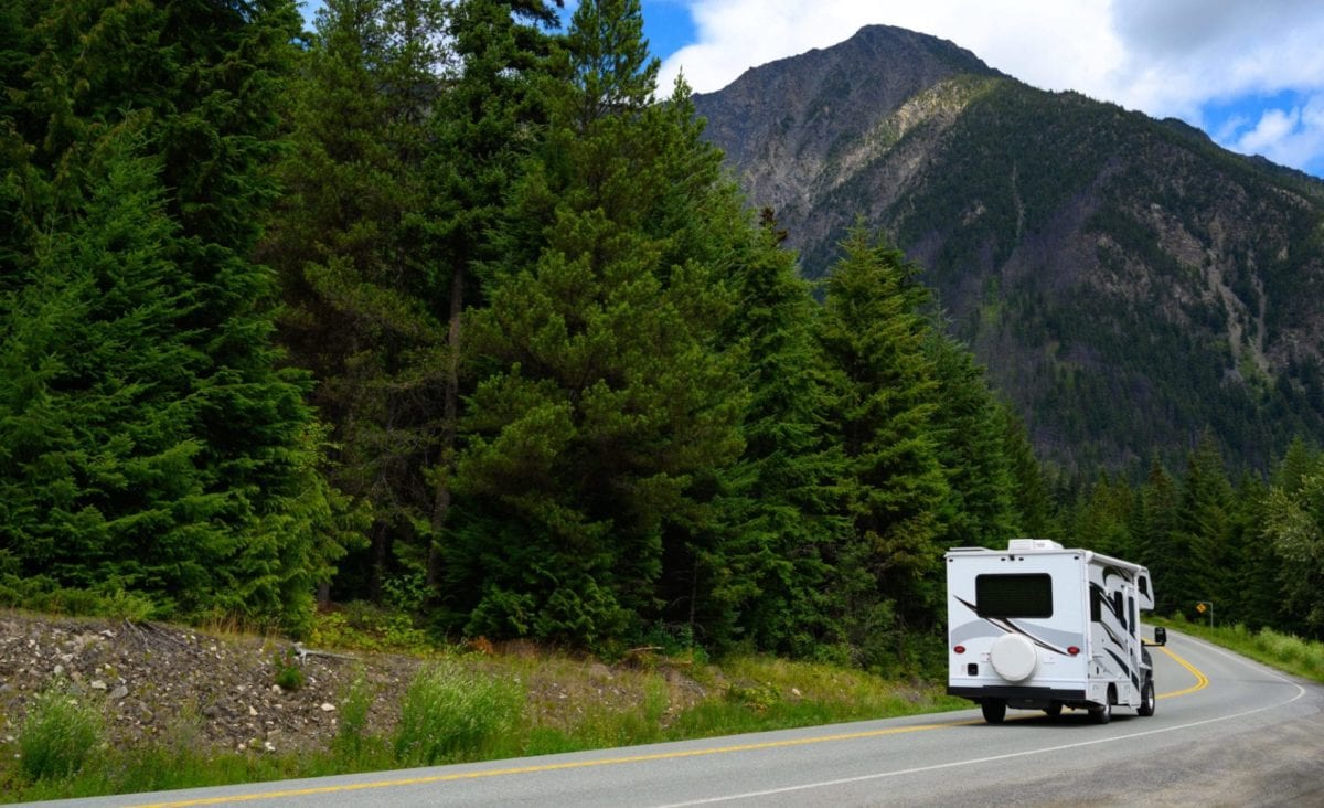 Camping-car se déplaçant sur route contre montagne